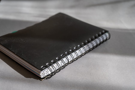 Black spring-loaded notebook against a gray background. Close-up of a closed notebook.