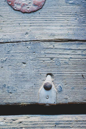 An old dirty board with an aluminum tag on it. The number 5 is embossed on the tag in the shape of an arrow.の写真素材