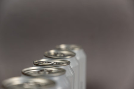A defocused shot of a line of tin cans. New enclosed Metallic silver individual beverage containers....