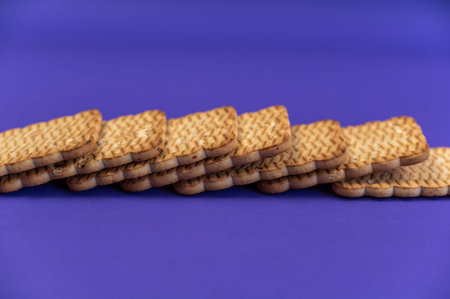 A stack of rectangular cookies against a blue background. Ready-to-eat treats with peanuts.