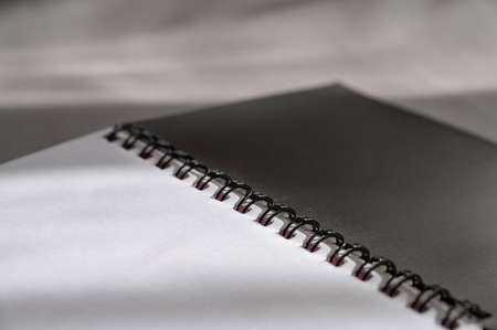Black spring-loaded notebook against a gray background. Close-up of an open notebook and blank white sheets.の写真素材