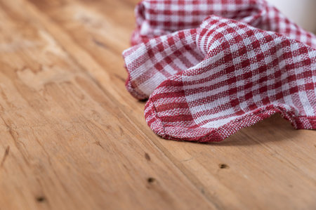 A red plaid kitchen towel lies on the countertop of a wooden table. Crumpled Towel or kitchen napkin on rough boards. close-up. selective focus.の写真素材