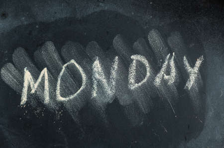 Semi-erased word MONDAY on black chalkboard. handwritten word. Fuzzy letters on a black surface. The concept of alternating days of the week. Calendarの写真素材