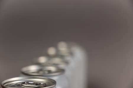 A defocused shot of a line of tin cans. New enclosed Metallic silver individual beverage containers. selective focus. Noise, blur, grain effectの写真素材
