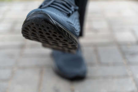 Close-up of male legs in blue sports shoes. Legs of an adult male sitting on an outdoor bench. daytime. selective focus.の写真素材