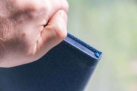 A man's hand holds a closed diary. Blue hardcover notebook. close-up. selective focus.