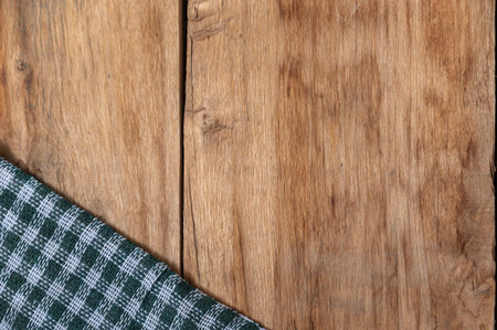 A green checkered cloth lies against a wooden background. A towel or kitchen napkin on the rough...