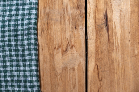 A green checkered cloth lies against a wooden background. A towel or kitchen napkin on the rough...