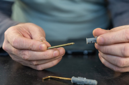 An adult male is holding an L-type screw with a dowel. A screw with a hook is used for mounting on...