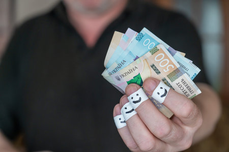 A grown man is holding money in his hand. Some Ukrainian hryvnia banknotes. The first phalanges of...