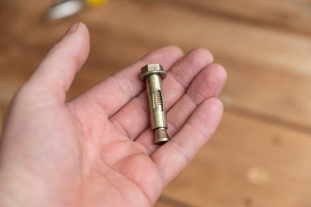 The anchor and nut are in the palm of my hand. A yellow bolt in the hand of a middle-aged man. A...