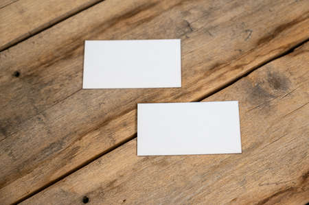 Blank business cards against a wooden background. White paper rectangles lie on top of old cracked boards. selective focus.の写真素材