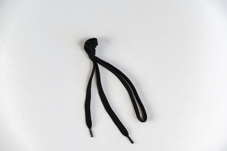 Black lace against a neutral background. Flat shoelace with tied knot. close-up. selective focus.