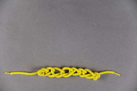 A yellow lanyard against a gray background. Round lace braided into loops. close-up. selective focus.の写真素材