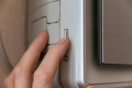Man turns on indoor air conditioner. His index finger presses the silver rectangular power button....