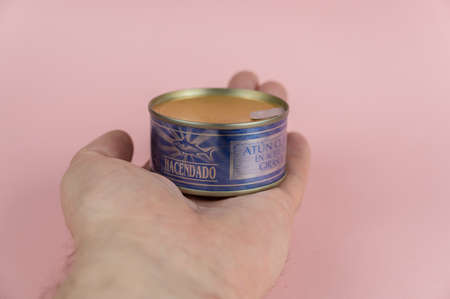 In the open palm of a man's hand lies a blue tin can. A tin of canned tuna in oil. Spanish manufacturer Hacendado. Ukraine, Mykolayiv -05 25 2022のeditorial素材