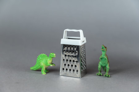 children's toys. Small grater and dinosaur miniatures against a gray background. Small green figures...