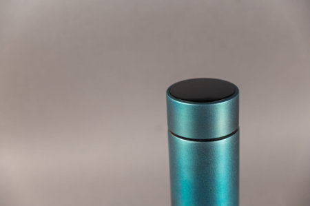 A modern flask against a gray background. Cylindrical vacuole flask in turquoise color. Container...