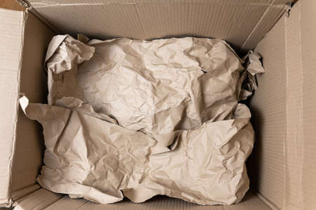 Open cardboard box. Crumpled wrapping paper inside the box. top view. selective focus.の写真素材