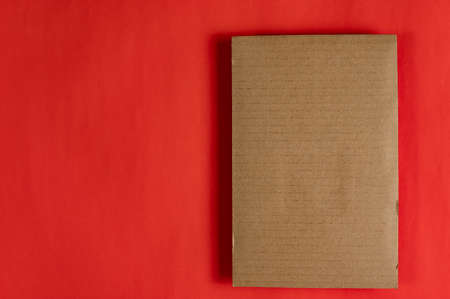 A rectangular piece of brown cardboard against a red background. Copy space for text and design elements. top view.の写真素材