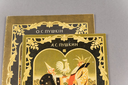 Russian fairy tale About Golden Cockerel in Russian and Ukrainian. Fairy tale by famous Russian writer and poet Alexander Pushkin. Two old books against grey. Ukraine, Mykolaiv - 06 23 2022のeditorial素材