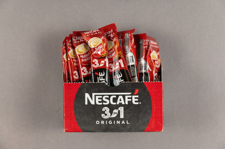 Nescafe instant coffee sticks in cardboard box on gray background. Coffee with milk and sugar. Nestle is a Swiss multinational corporation. Its headquarters in Vevey. Ukraine, Mykolaiv - 06 22 2022.のeditorial素材