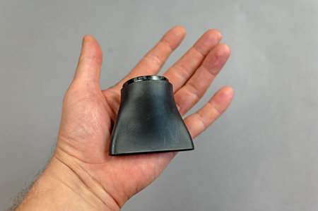 The man is holding the concentrator nozzle for the electric hair dryer. The nozzle is designed to create a directional flow of volumizing hair and massage. gray background. indoors. close-up.の写真素材