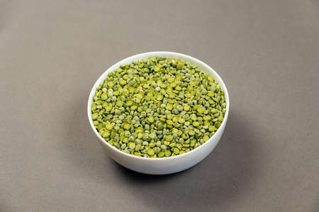 Uncooked food. Dry split peas in a white ceramic bowl. green beans. gray background. View from above at an angle. selective focus.の写真素材
