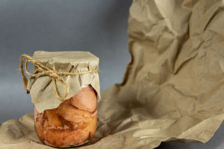 A glass jar of canned meat. Homemade stew in front of the gray background. Slices of appetizing meat tightly packed in a transparent jar. Food ready to eat. close-up. selective focus.の写真素材