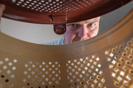 Man peeks inside a brown pet carrier basket. Adult male looking closely at the cat or puppy sitting inside the plastic carrier. inside view. selective focus.の写真素材