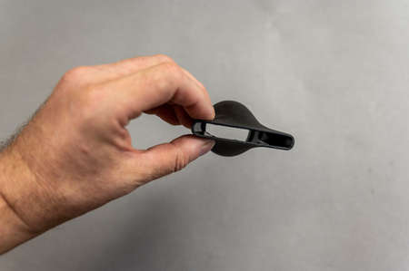 The man is holding the concentrator nozzle for the electric hair dryer. The nozzle is designed to create a directional flow of volumizing hair and massage. gray background. indoors. close-up.の写真素材