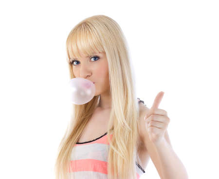 Pretty woman giving thumbs up and blowing bubble with bubble gum over whiteの写真素材