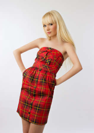 Beautiful young woman in red dress with long blonde hair on grey background の写真素材