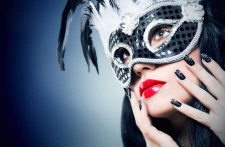 Beautiful young woman in black carnival mask with manicureの写真素材