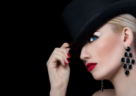Beautiful girl in hat with red lipstick on black backgroundの写真素材