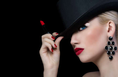 Beautiful girl in hat with red lipstick on black backgroundの写真素材
