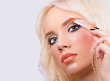 Beautiful blonde girl with perfect makeup on grey background