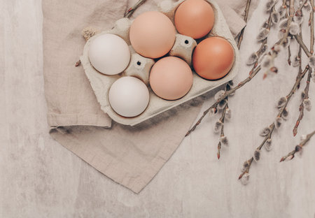 Easter eggs in a box with willow branches on grey background