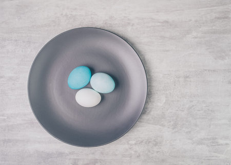 Easter blue eggs on grey plate on a grey table, rustic style. 