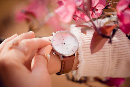 Stylish white watch on woman hand in flowersの写真素材