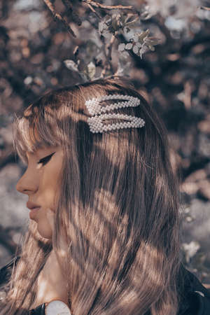 Close up portrait of a young blonde woman with natural hairstyle, wearing pearl hair clips.の写真素材