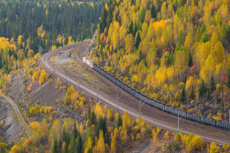 A freight train moves by rail in the mountains of Siberia, in the fall.のeditorial素材