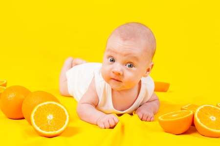 baby lying on the tummy with orangesの写真素材