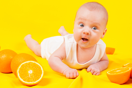 baby lying on the tummy with orangesの写真素材