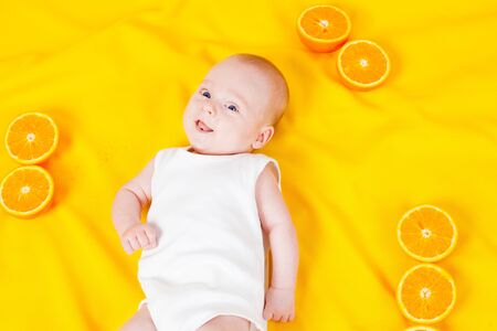baby lying on the tummy with orangesの写真素材