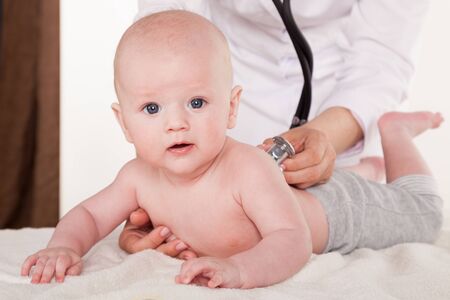 the doctor listens to the baby newbornの写真素材