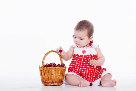a little girl sits with a basket with cherriesの写真素材