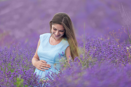 a pregnant woman walks through a field of lavenderの写真素材