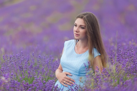 a pregnant woman walks through a field of lavenderの写真素材