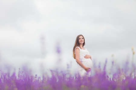 Lavender field and a happy pregnant womanの写真素材